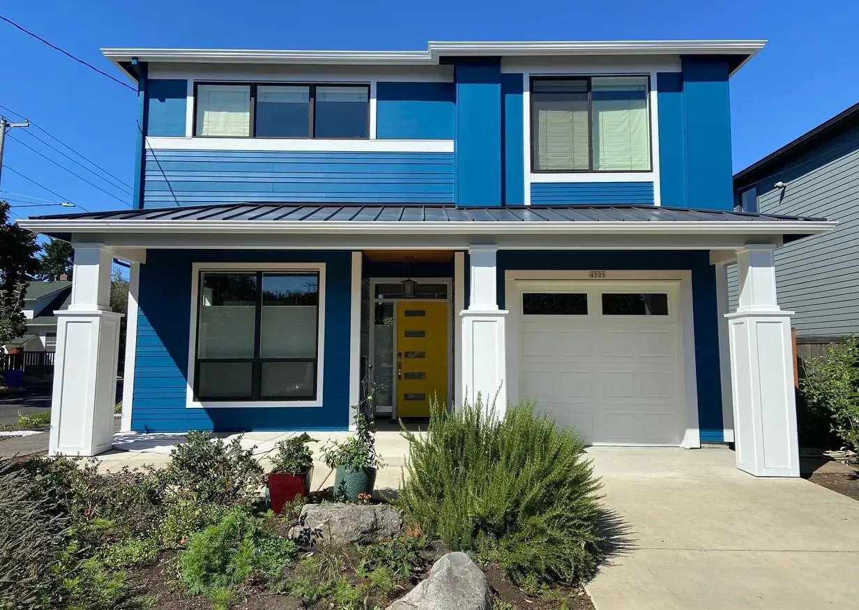 Modern two-story home painted bold blue with crisp white trim and a yellow front door