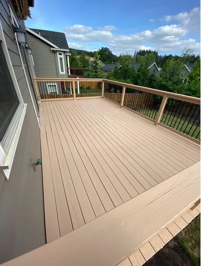 Finished tan deck boards and railing overlooking a green yard
