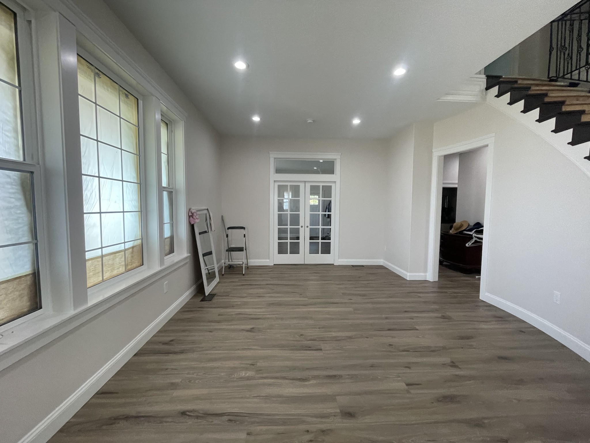 Bright interior with white walls and trim, windows masked off during a paint job