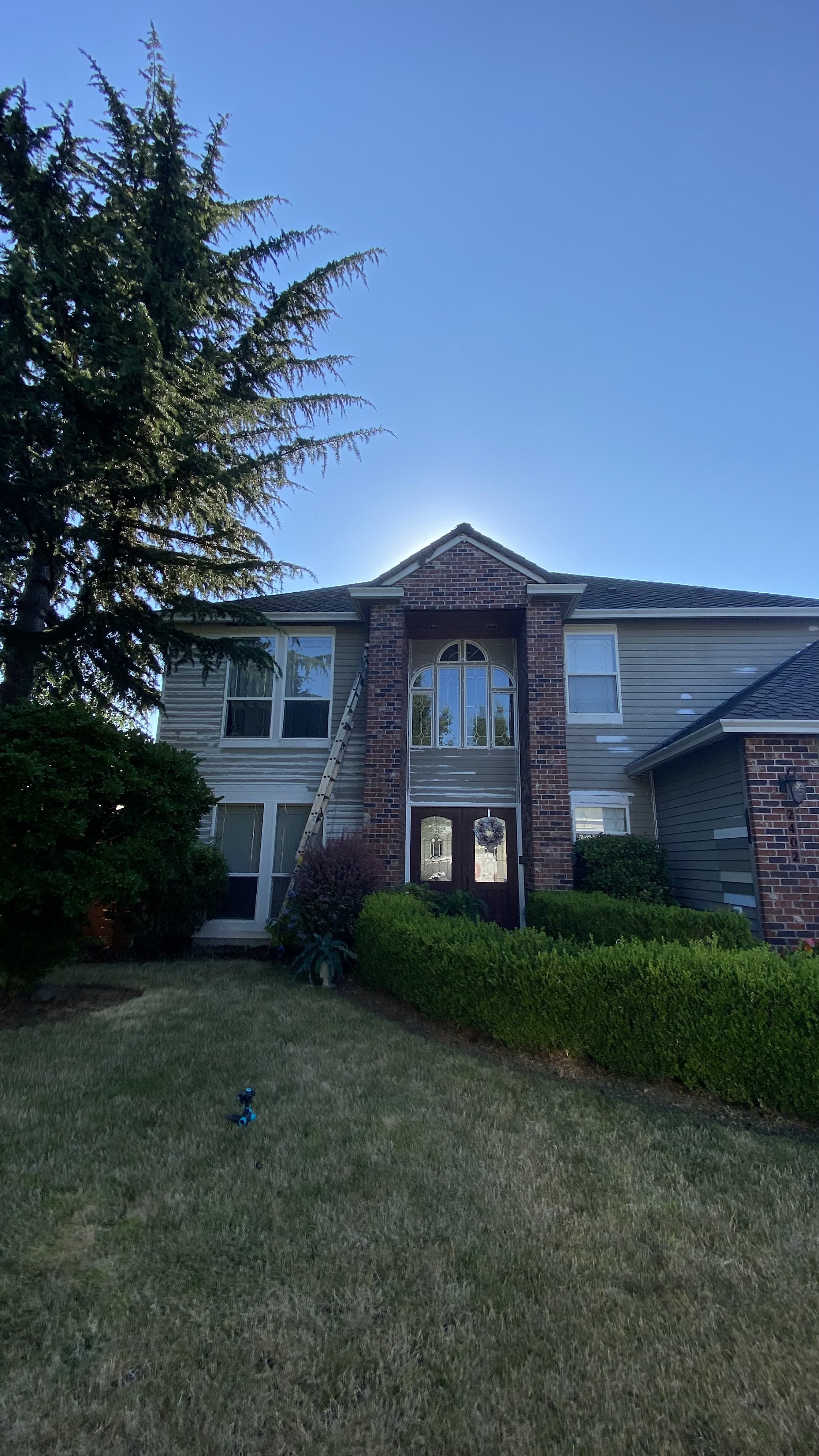 Two-story home with a brick entry and freshly painted siding, lawn in front